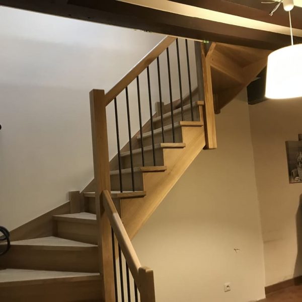 Escalier en chêne avec un éclairage suspendu et une rampe en bois élégante.