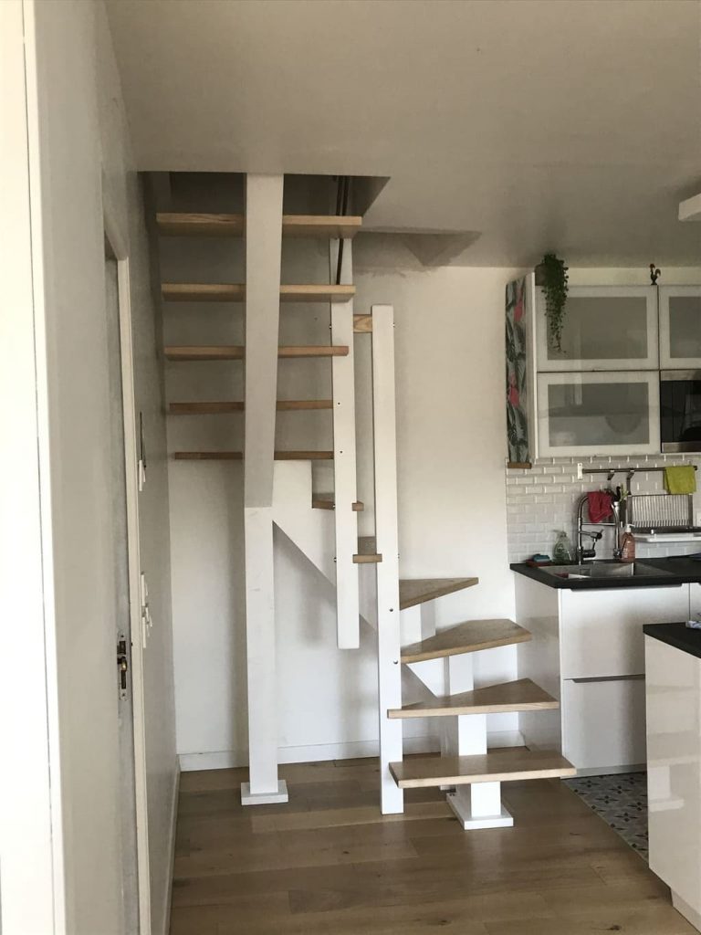 Cuisine moderne avec un escalier central en frêne à deux quarts tournants, créant une ambiance chaleureuse et accueillante.