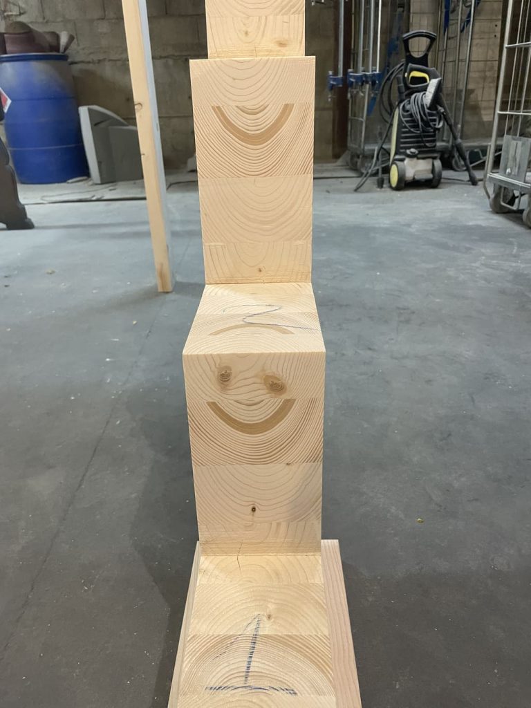 Une pile de blocs en bois avec un visage souriant, fabriquée en limon central lamelé collé de sapin.
