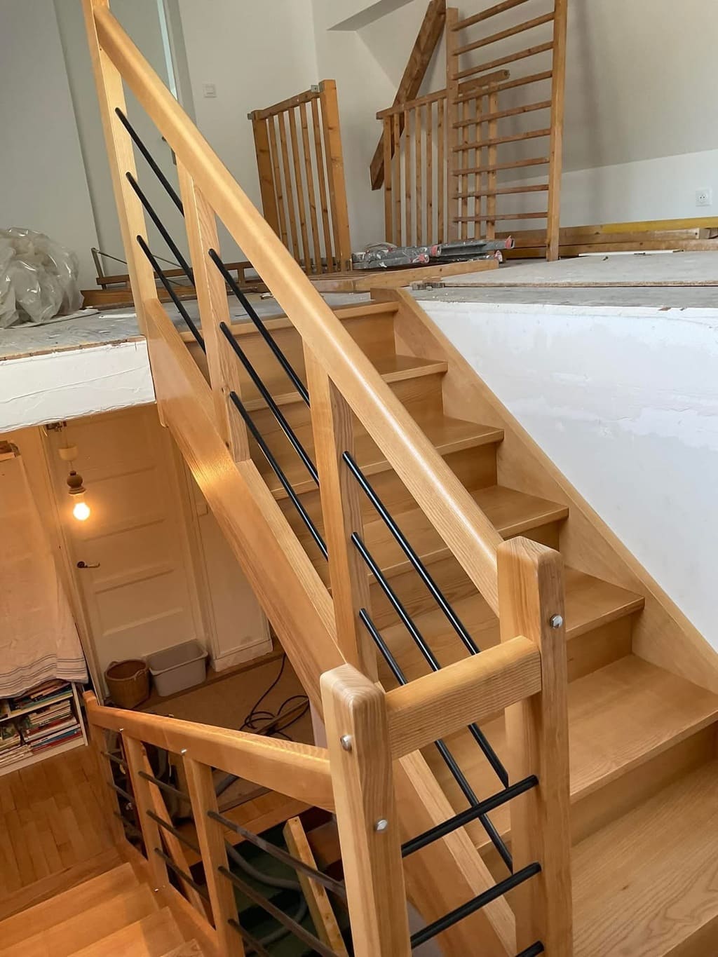 Escalier en bois avec rampes en métal et garde-corps en bois, offrant une esthétique chaleureuse et moderne.